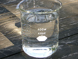 Photo: Beaker of water on table with sunlight on it